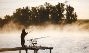 Carp fishing in the wind - man casting into windy lake