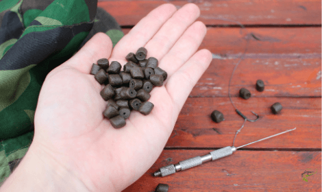 carp fishing with pellets - man holding handful of driller carp pellets