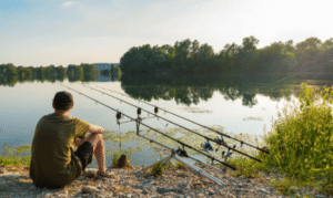 how to read the water when carp fishing - man sitting beside river with carp rods
